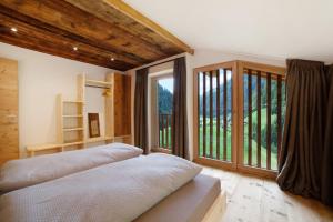 a bedroom with two beds and a large window at Herrischner Apartement 1 in Moso