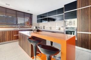 a kitchen with an orange counter and stools at Casa dos Pinheiros in Apúlia