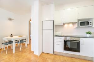 a kitchen with white cabinets and a table with chairs at White Sands 306 in Arenal d'en Castell +12 photos