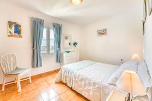 a bedroom with a bed and a chair and a window at White Sands 306 in Arenal d'en Castell