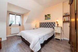 a bedroom with a bed and a nightstand and two windows at La Maison Bleue 3 étoiles in Plouhinec