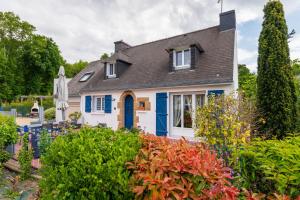 a white house with blue doors and a yard at La Maison Bleue 3 étoiles in Plouhinec