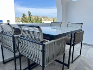 a dining table and chairs with a view of the ocean at aeolian blu 4 in Parikia