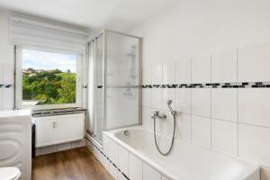 a white bathroom with a tub and a window at Fewo Schneider Bad Wildungen in Bad Wildungen +15 photos