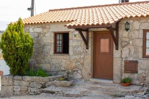 a stone house with a brown door and a tree at Casa Da Calçada - Turismo Sortelha in Sortelha