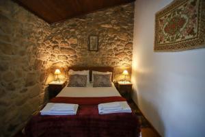 a bedroom with a bed in a stone wall at Casa Da Calçada - Turismo Sortelha in Sortelha
