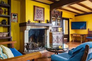 a living room with a fireplace and yellow walls at El Rincón Del Duende in Pedro Bernardo