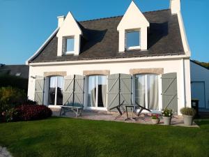 a white house with black shuttered windows at Chambres Er Vingle - Locmariaquer in Locmariaquer