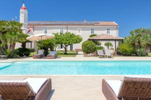 a swimming pool with chairs and a building at Dimora Sella - Casa Monica in Alghero