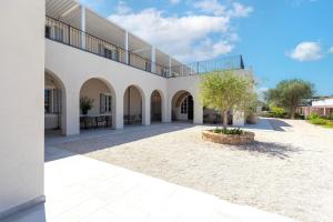 a large white building with a tree in a courtyard at Dimora Sella - Casa Monica in Alghero