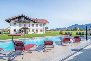 a pool with chairs and tables next to a house at 5 Sterne Ferienwohnung Sissi in Übersee