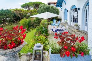a garden with red flowers and a white house at L'annexe - Chambre in Ciboure