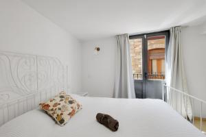 a bedroom with a white bed with a pillow and a window at Wonderful loft centre Manresa in Manresa
