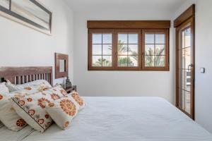 a bedroom with a bed with pillows and a window at Casa en la playa con piscinas A in Puerto Marino +20 photos