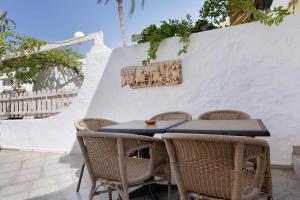 a table with wicker chairs and a white wall at Apartamento Las Flores4 in San Bartolomé