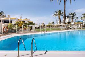 a large blue swimming pool with palm trees at Apartamento Las Flores4 in San Bartolomé +9 photos