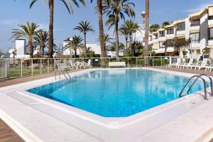 a pool at a resort with palm trees at Apartamento Las Flores4 in San Bartolomé