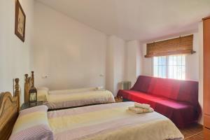 a room with three beds and a red couch at Casa Ginés in Iznájar +25 photos