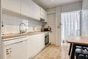 a kitchen with white cabinets and a sink and a table at Apartamento de playa en Cullera in Cullera