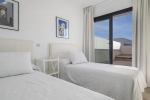 two beds in a white room with a window at Casa África in Zahara de los Atunes +17 photos