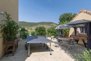 a ping pong table and an umbrella in a patio at Appartement N°2 - Piscine Partagée in Lagorce