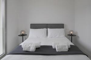 a bedroom with a bed with white sheets and pillows at Baseventuno 3 bilocale piano terra in Sirmione +19 photos