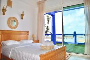 a bedroom with a bed and a large window at Villa with pool and beach access in Ben Slimane +40 photos