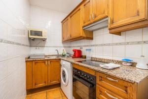 a kitchen with wooden cabinets and a washing machine at Apartament Garrota in Olp