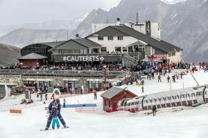a group of people skiing in the snow in front of a ski lodge at L'Izard Piscine, Jacuzzi, Parking in Cauterets