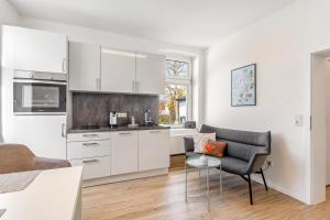 a kitchen with white cabinets and a chair and a table at Ferienwohnung am Wall in Soest