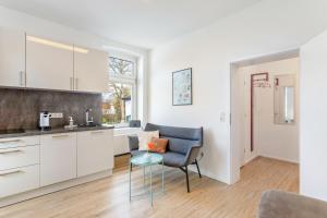 a kitchen with white cabinets and a chair and a table at Ferienwohnung am Wall in Soest +18 photos