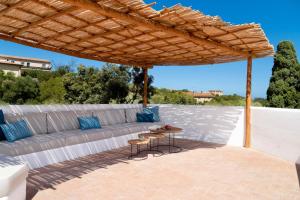 a patio with a couch under a wooden pergola at Casa Le Rocce San Pantaleo in San Pantaleo