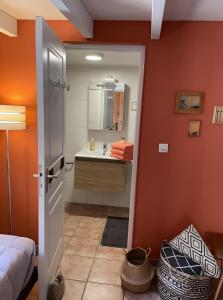 a bedroom with orange walls and a bathroom with a sink at Chambres D'hôtes du Pentadou in Felzins +26 photos
