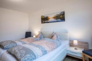 a white bed with blue and pink pillows on it at Ferienwohnung Nr 5 Sonnenschein in Höchenschwand