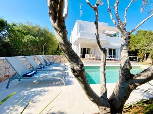 a row of lounge chairs next to a swimming pool at Villa Es Ratolí in Cacla D'or