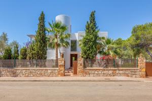 a white house with a stone fence and palm trees at Villa Es Ratolí in Cacla D'or