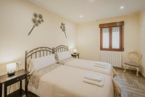 a white bedroom with two beds and a window at Torres 1 in Quintana de Valdivielso