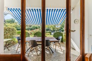 a glass door leading to a patio with a table and chairs at Appartement Rose Mousse - Abatilles in Arcachon