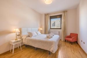 a bedroom with a bed and a red chair at Central, Spacious Parking in Granada