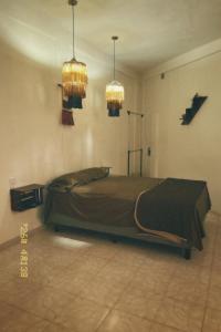 a bedroom with a bed and two chandeliers at Casa Rouge Alojamiento Cerca de Uman in Mérida