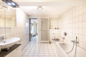 a white bathroom with a tub and a sink at Alb Rose Ferienwohnung in Sonnenbühl +21 photos