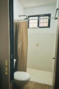 a bathroom with a toilet and a shower at Casa Rouge Alojamiento Cerca de Uman in Mérida