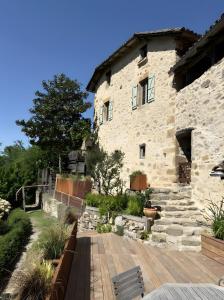a stone building with a wooden deck in front of it at Chambres D'hôtes du Pentadou in Felzins