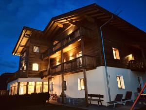 a large wooden house at night with two chairs at Residence Zirmer in Castelrotto