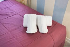 two white towels on top of a purple bed at 5 Terre - Lerici - Piccolo Golfo in Lerici