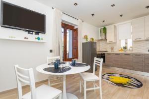 a kitchen with a white table and chairs and a tv at MSuite Etna Sicily in Macchia