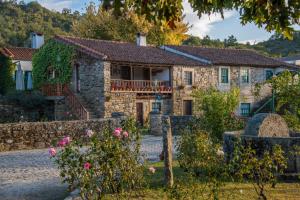 an old stone house with roses in front of it at Villa Jerusalém - Casa de Campo in Romeu