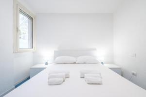 a white bedroom with a large white bed with two white towels at Da doddo e beby in Santa Margherita di Pula