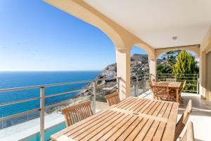 a balcony with a wooden table and chairs and the ocean at Villa Mina - First Line Villa in El Campello