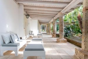 a row of white benches sitting on a patio at Villa Riggia - La Masseria in Nardò